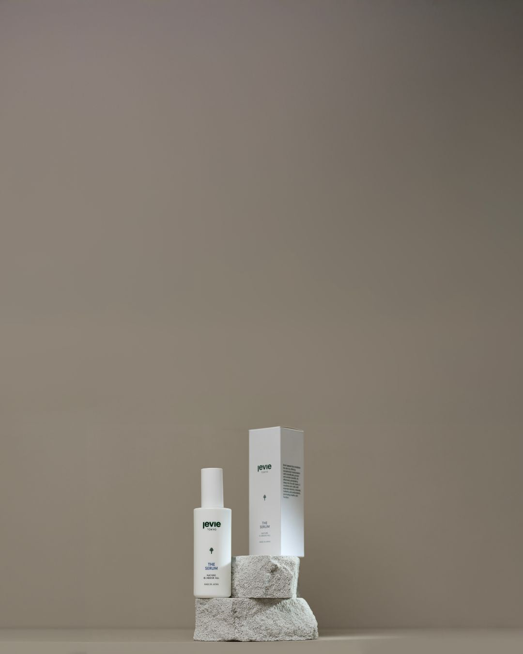 Two skincare products on a stone block against a plain background