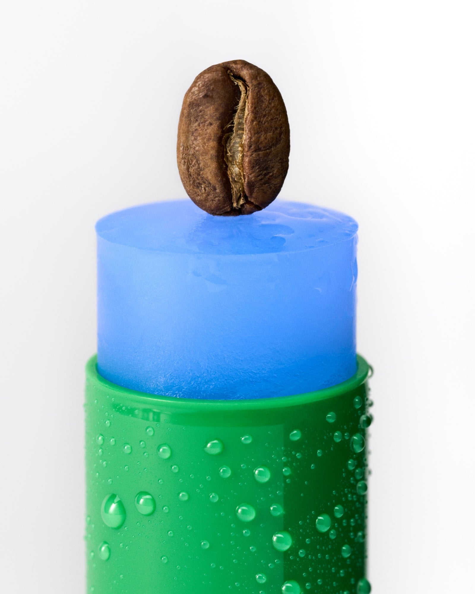 Blue stick with a coffee bean on top, surrounded by water droplets on a white background