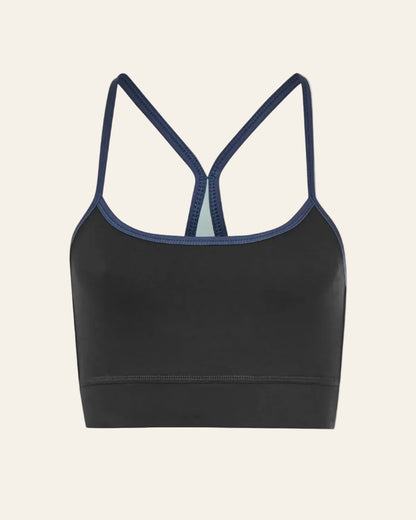 Black sports bra with thin straps on a beige background