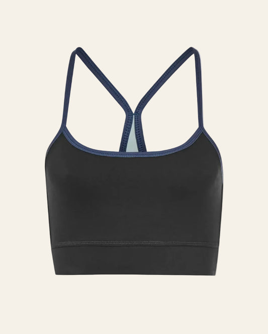 Black sports bra with thin straps on a beige background