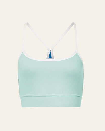 Light blue sports bra with white straps on a beige background