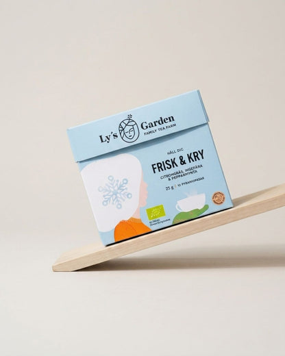 Box of Ly's Garden tea on a wooden stand with a light background
