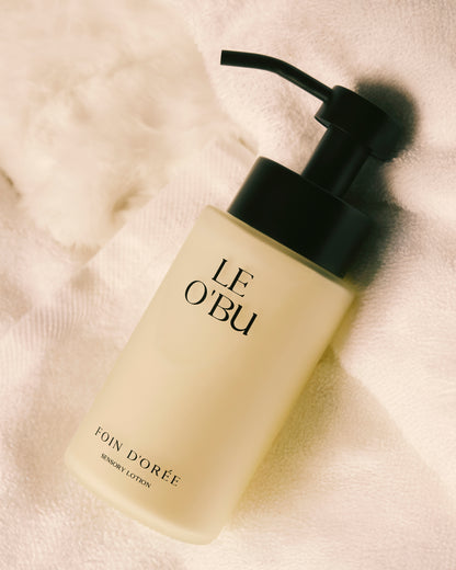 LE O'BU lotion bottle with pump on a textured beige background