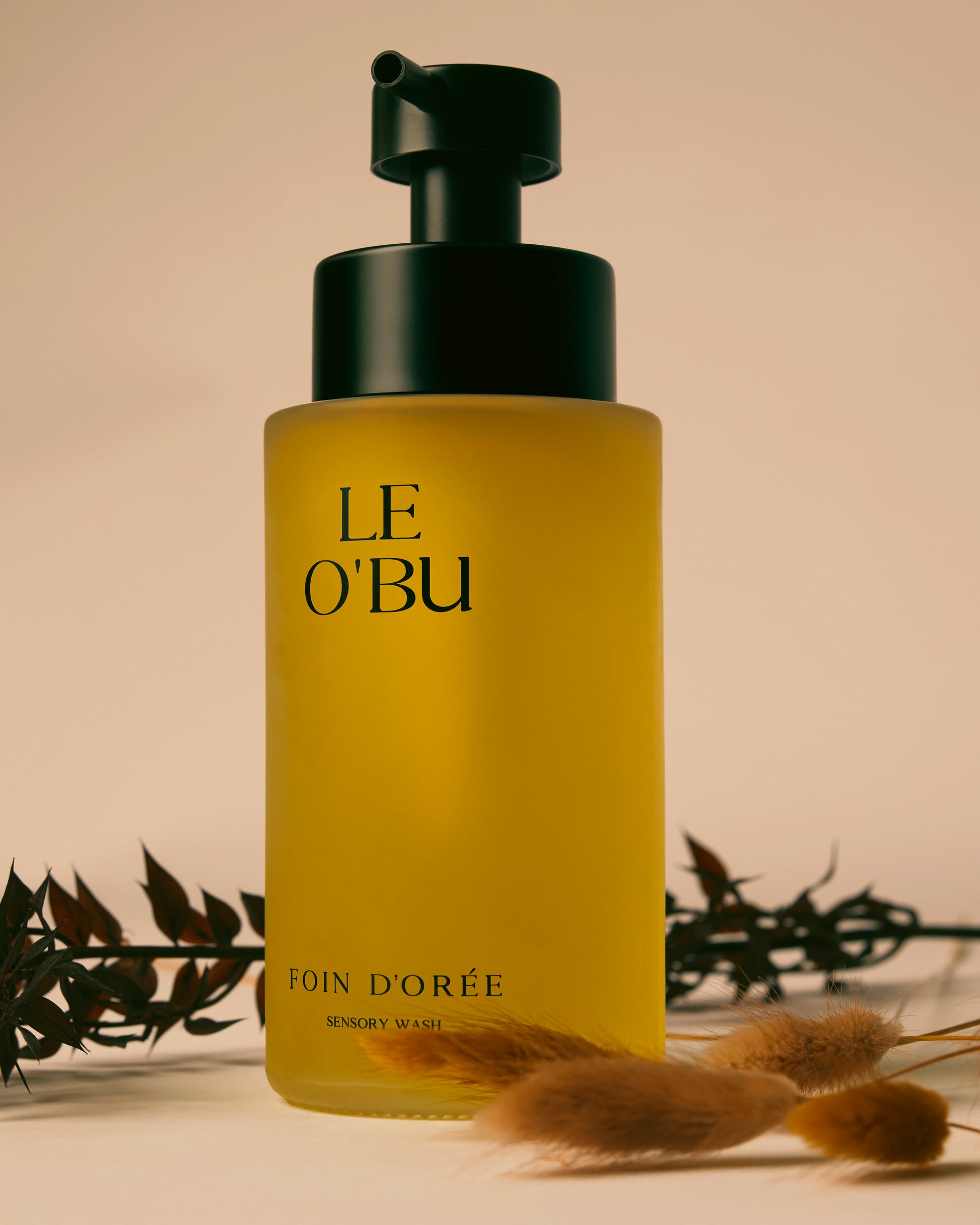 Yellow bottle with black cap labeled 'LE O'BU' on a beige background