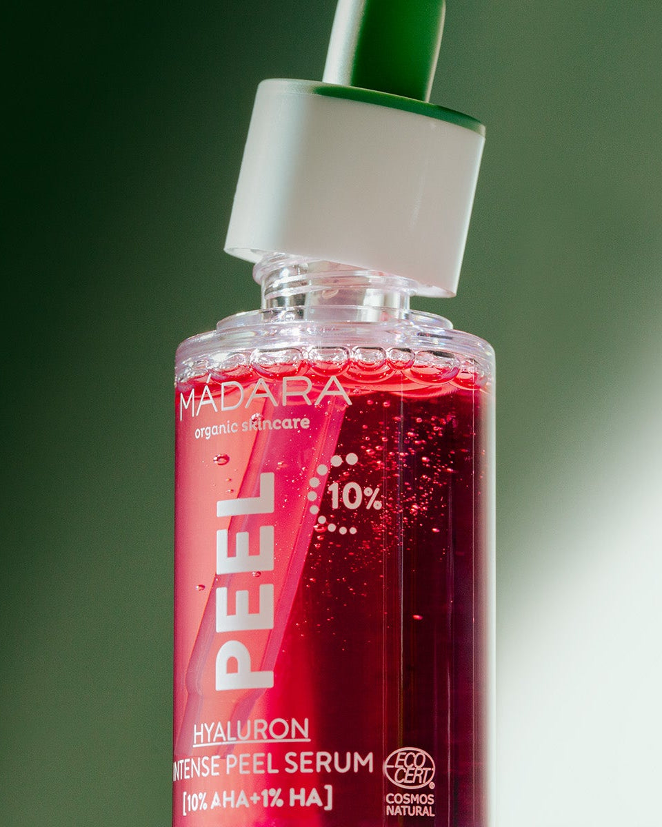 Red serum bottle with dropper labeled 'MADARA' on a green background