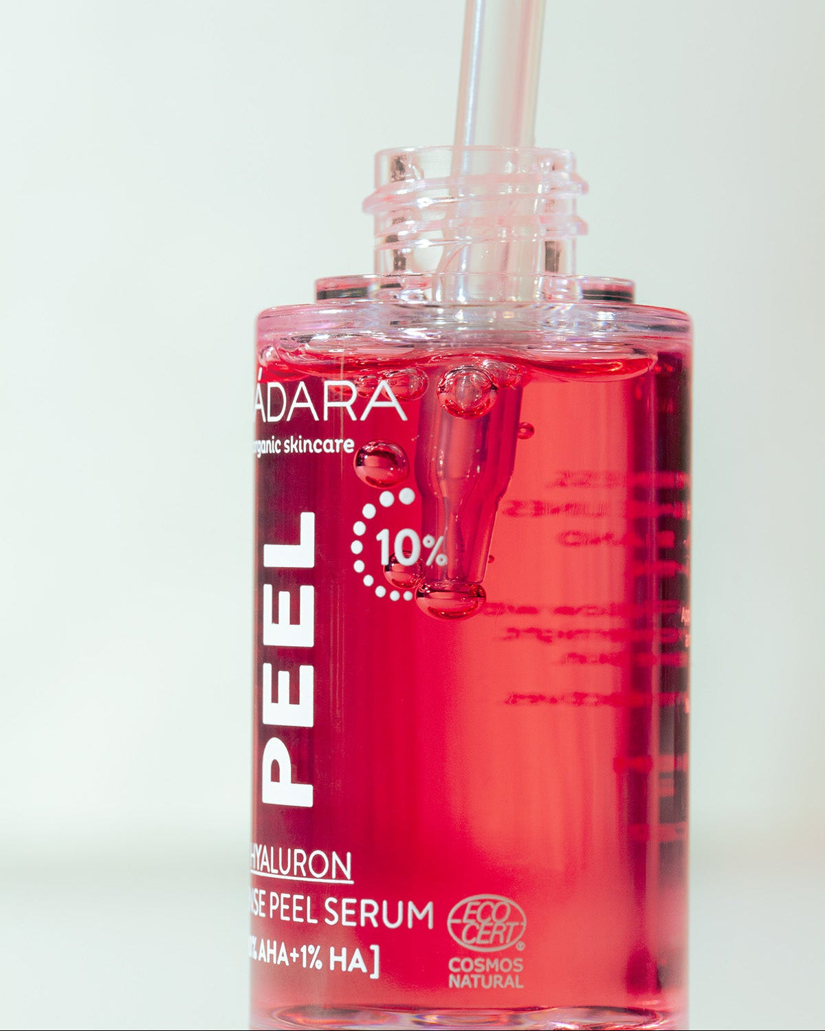 Red serum bottle with dropper labeled 'MADARA' on a light background