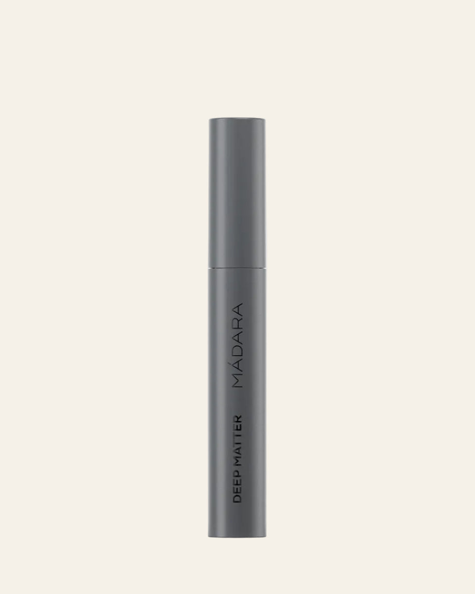 Dark gray cosmetic tube with 'MADARA' branding on a light gray background