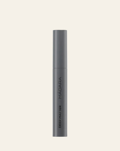 Dark gray cosmetic tube with 'MADARA' branding on a light gray background
